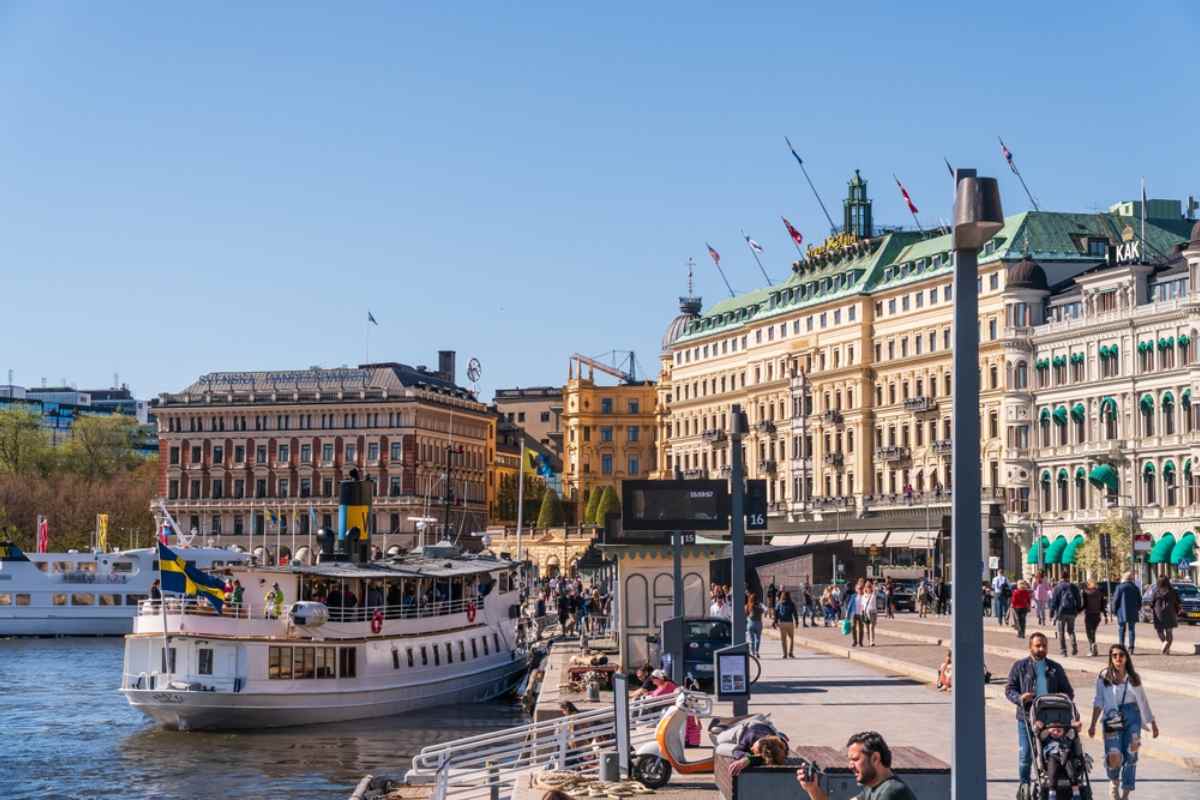 Overview of central Stockholm on a sunny day with tour boats in front of the city's Grand Hotel.